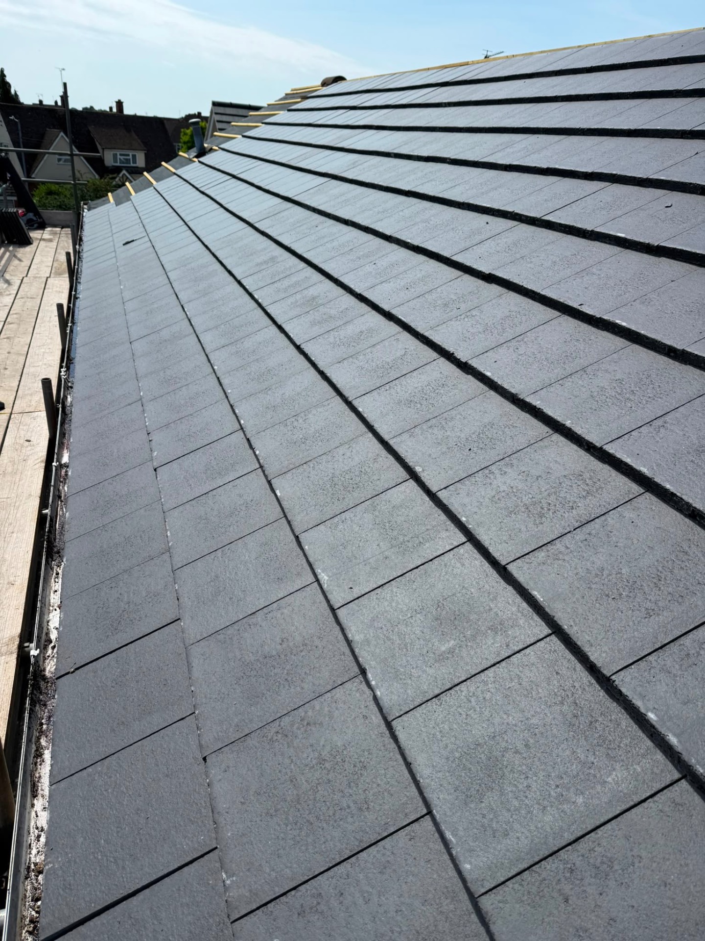 Sweeping view of a freshly finished grey slate roof rising toward the ridge