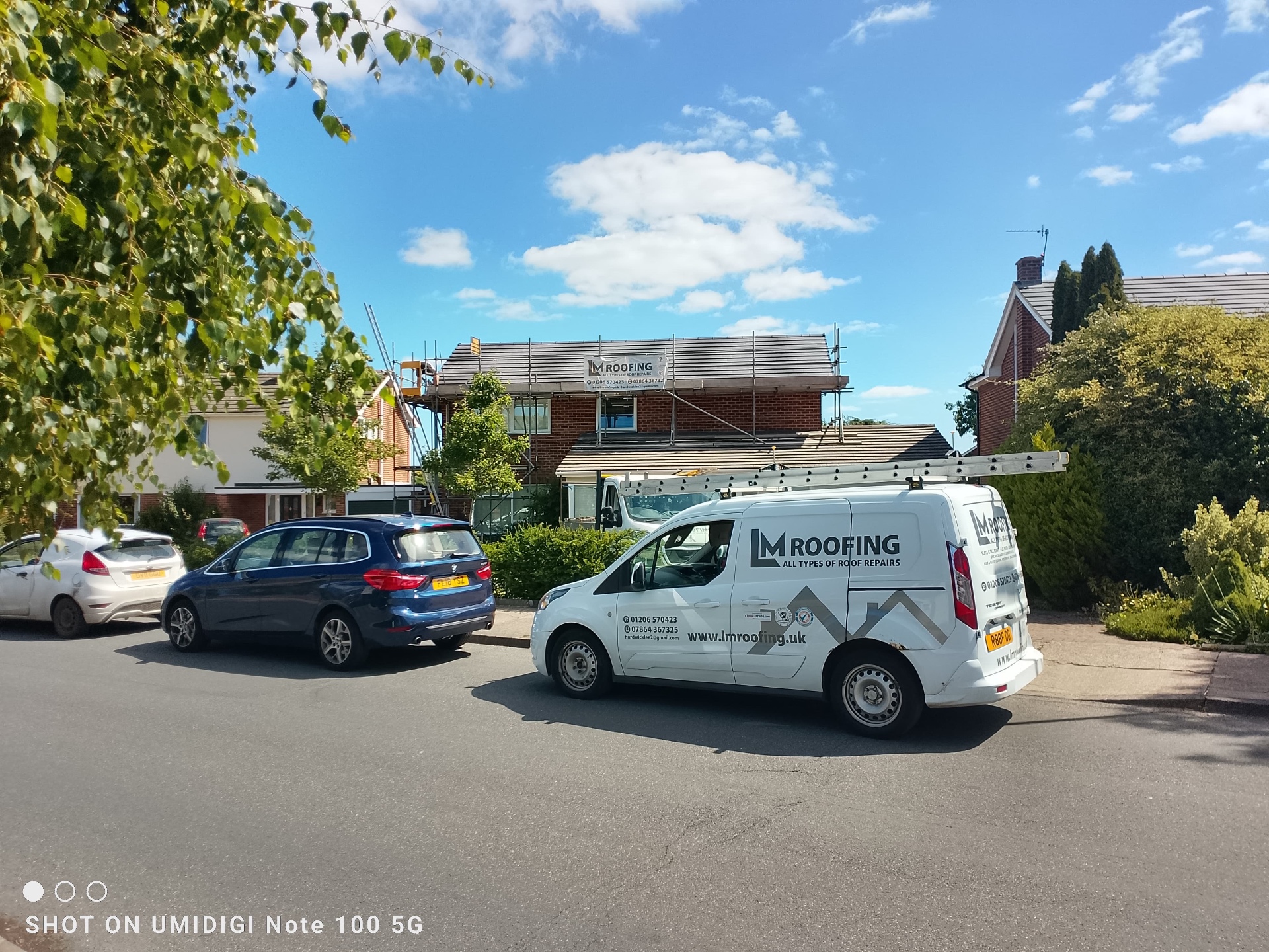 LM Roofing branded van parked outside a scaffolded re-roof project in progress