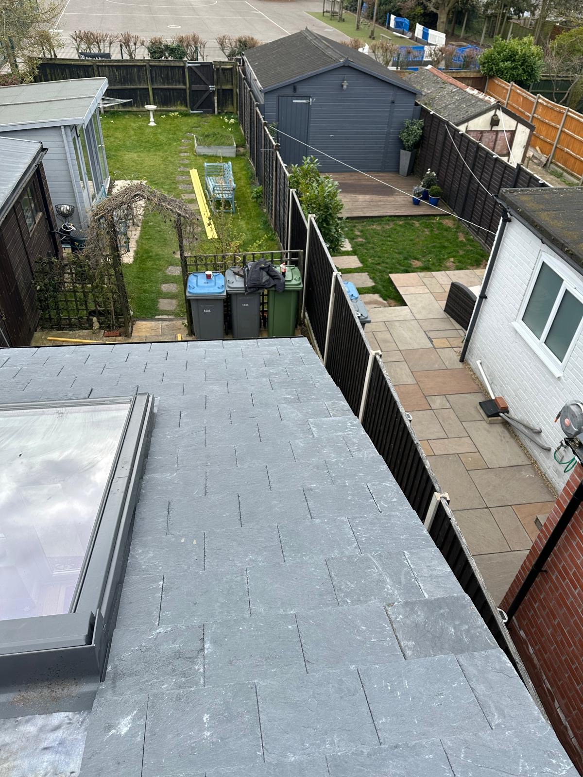 Finished slate flat-pitch roof with skylight overlooking garden