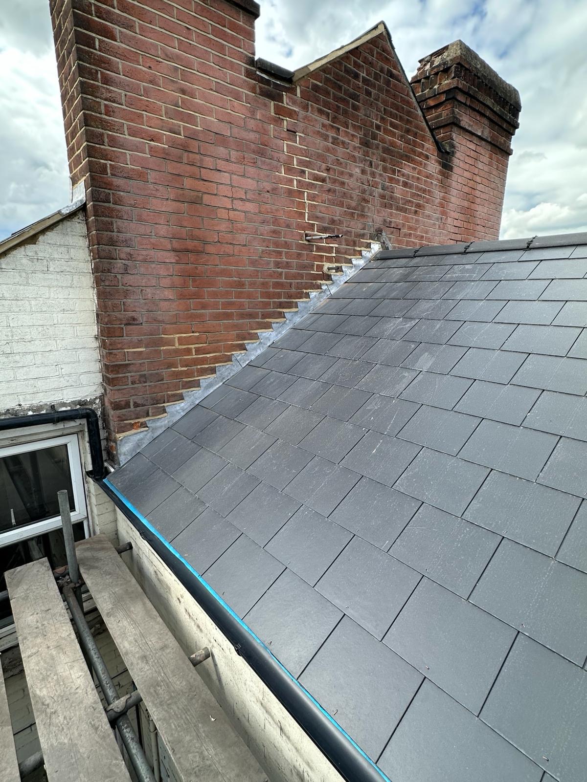 Crisp new slate roof with precision stepped lead flashing to a party wall
