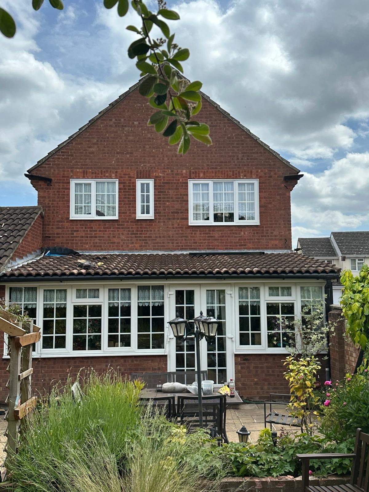 Detached red brick home with tiled conservatory roof and repointed chimney