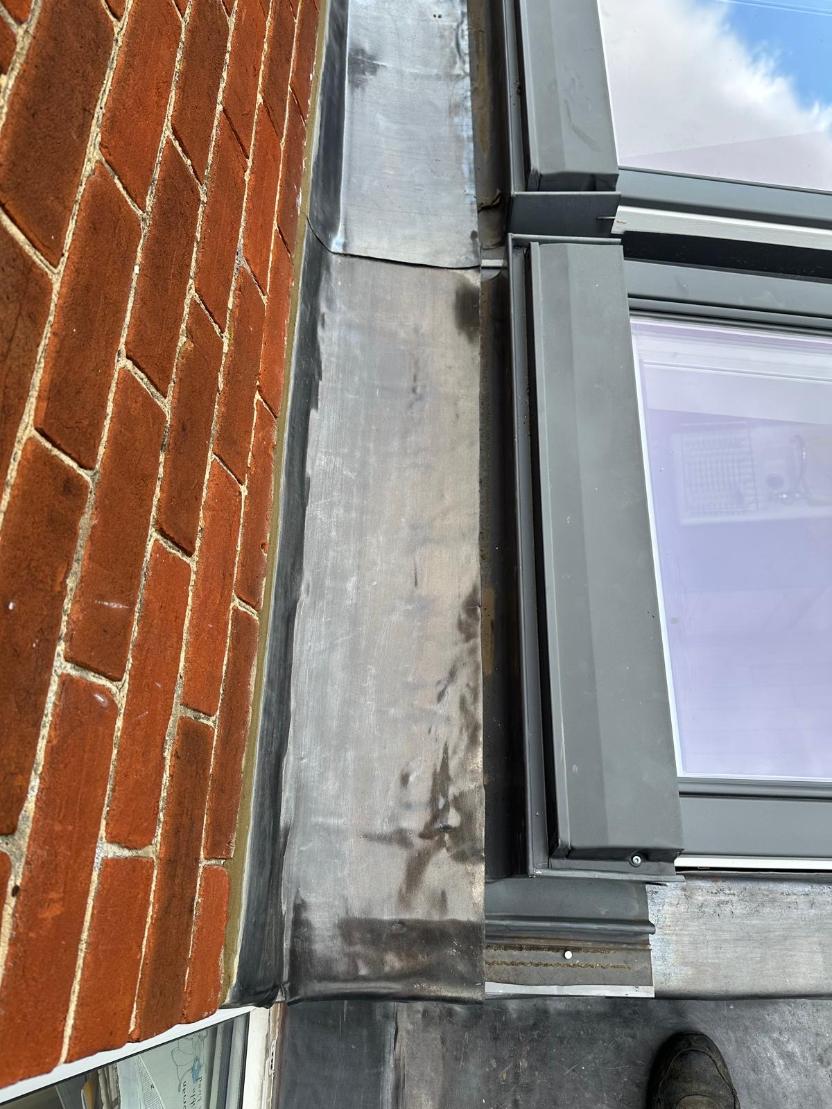 Precision lead flashing detail against red brickwork and skylight