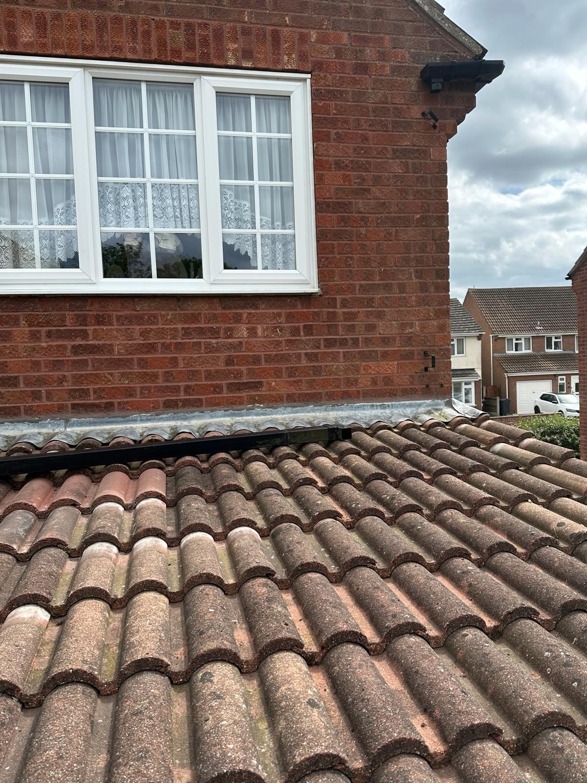 Fresh lead flashing dressed above pantile roof onto red brick wall
