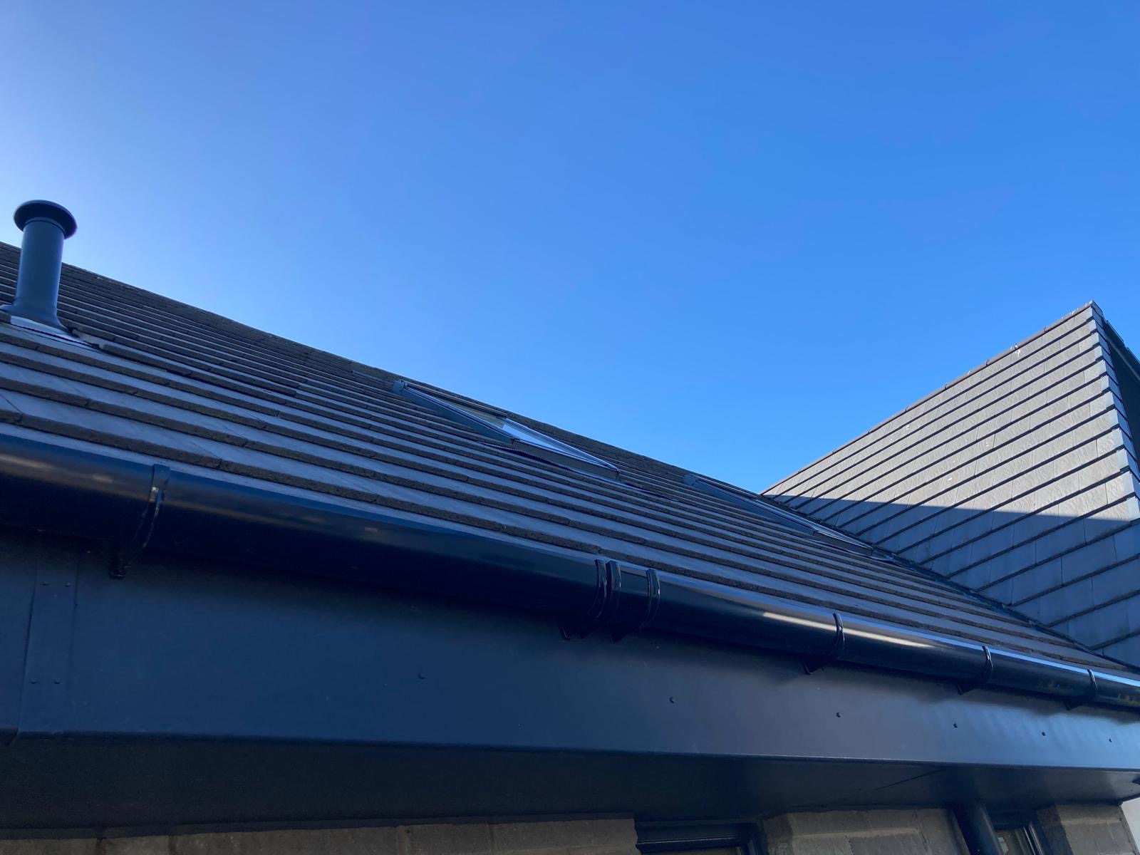 New slate roof with glossy black seamless guttering and downpipes
