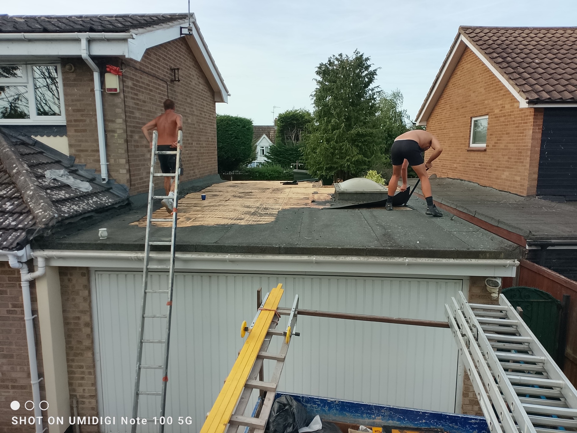 LM Roofing team stripping old felt from a garage flat roof to expose timber deck