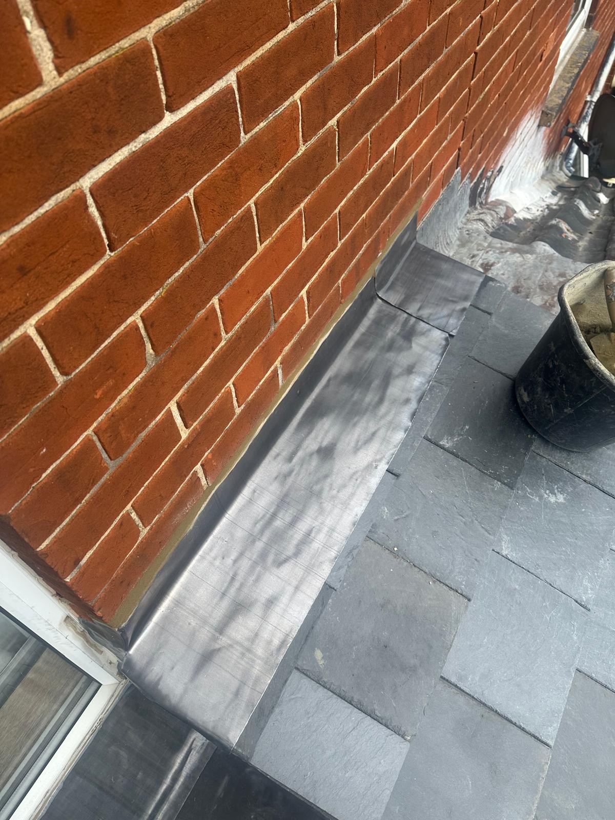 Lead work stepped down brick wall onto slate covered roof