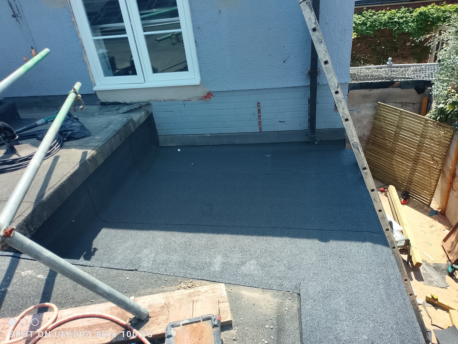 Freshly torched EPDM-style flat roof dressed neatly up to painted brickwork