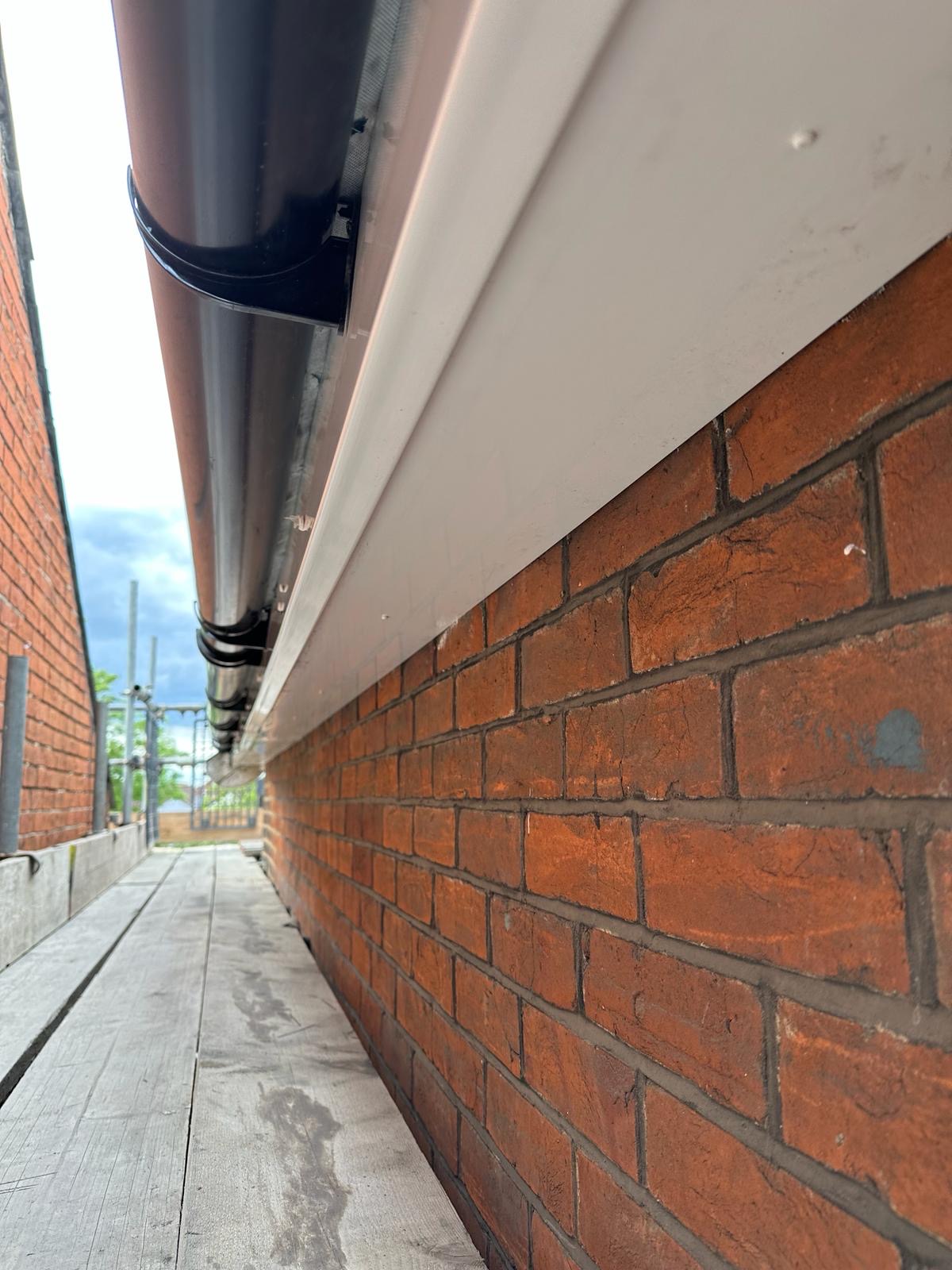 New white fascia, soffit and black seamless guttering on red brick home