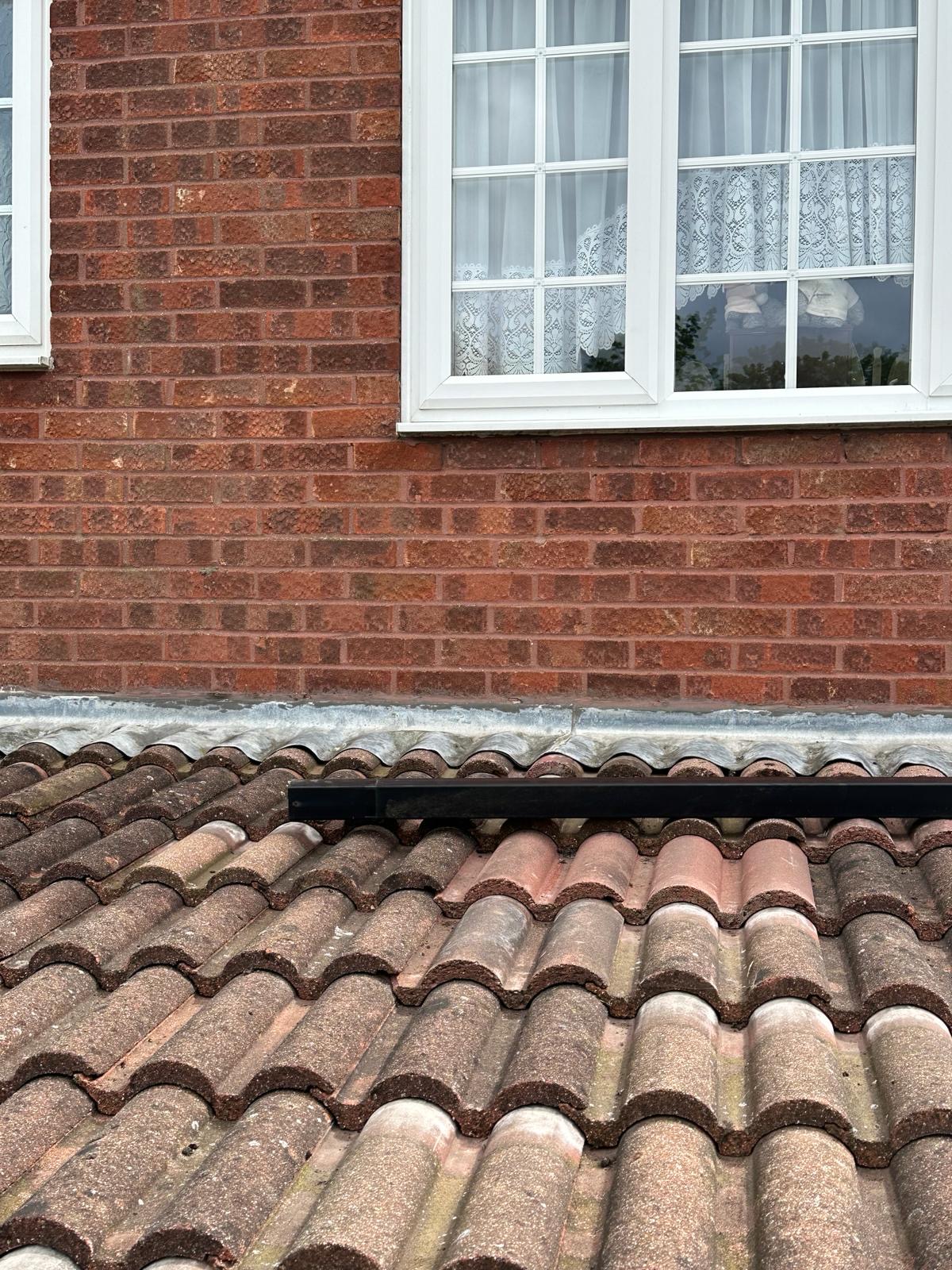 Close-up of neat lead soaker detail between pantile roof and brickwork