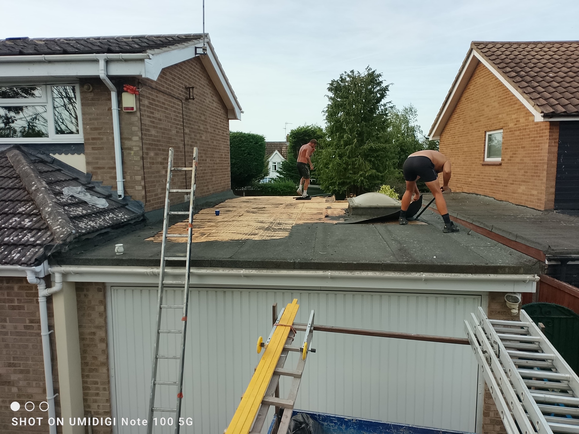 Roofers preparing garage flat roof for new torch-on felt covering