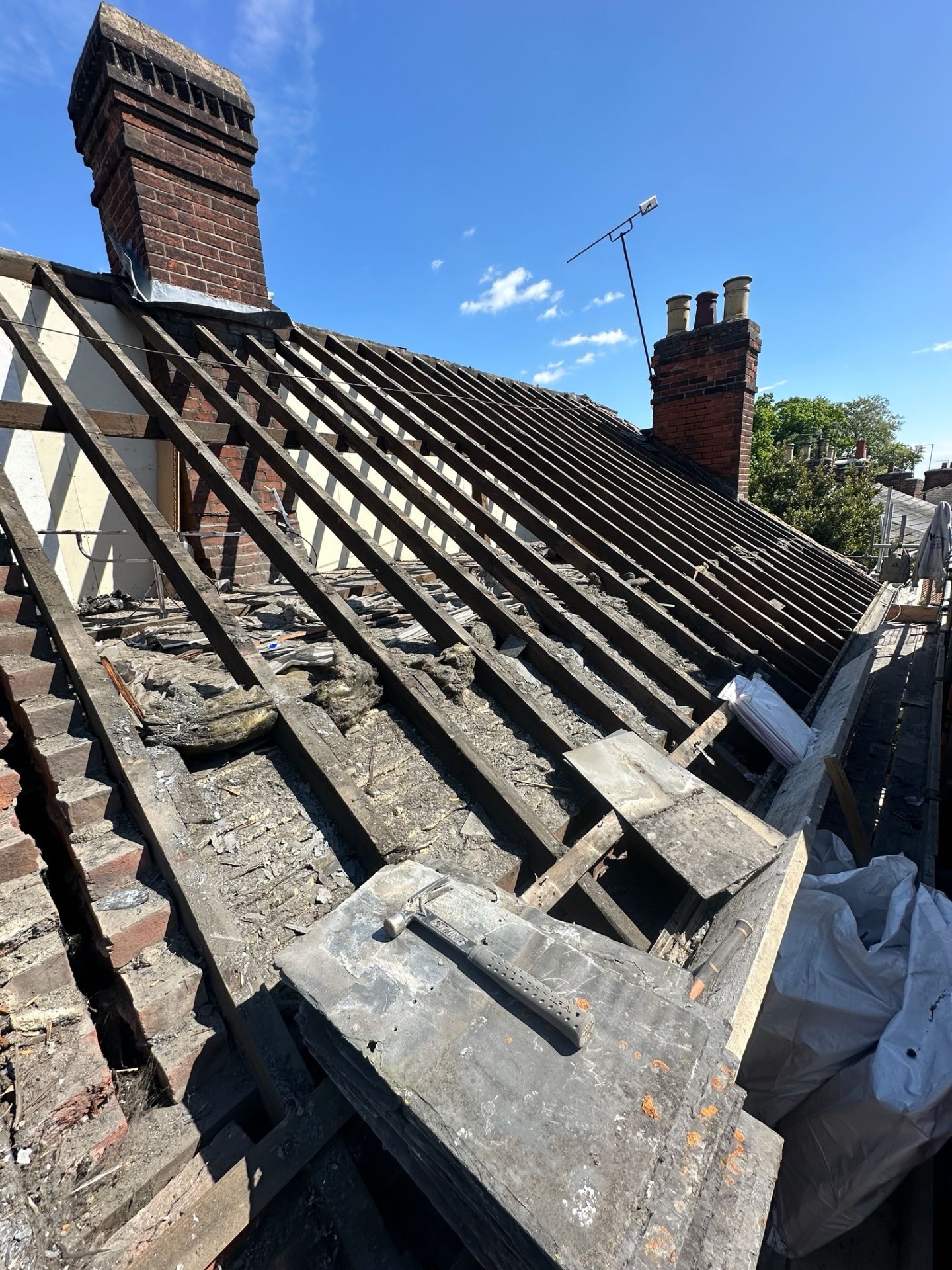 Old roof stripped back to rafters beside original brick chimney stack