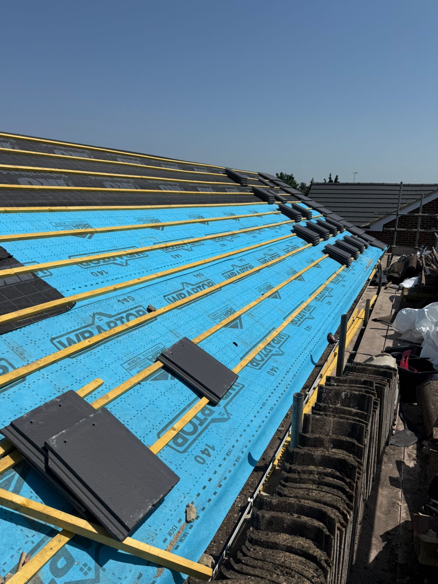 Fresh Wraptor membrane and battens with slate tiles stacked ready to lay