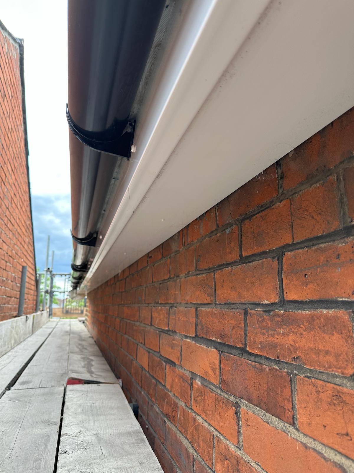 Crisp white uPVC fascia and black round-line guttering on brick terrace
