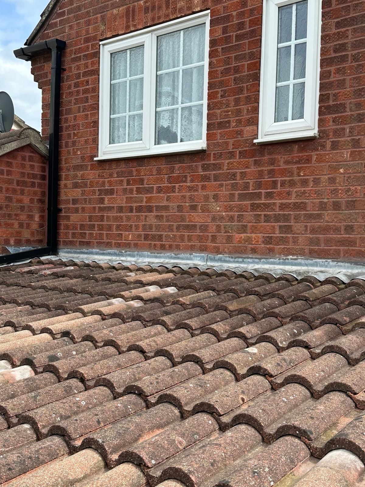 New lead flashing running along brick wall above pantile roof