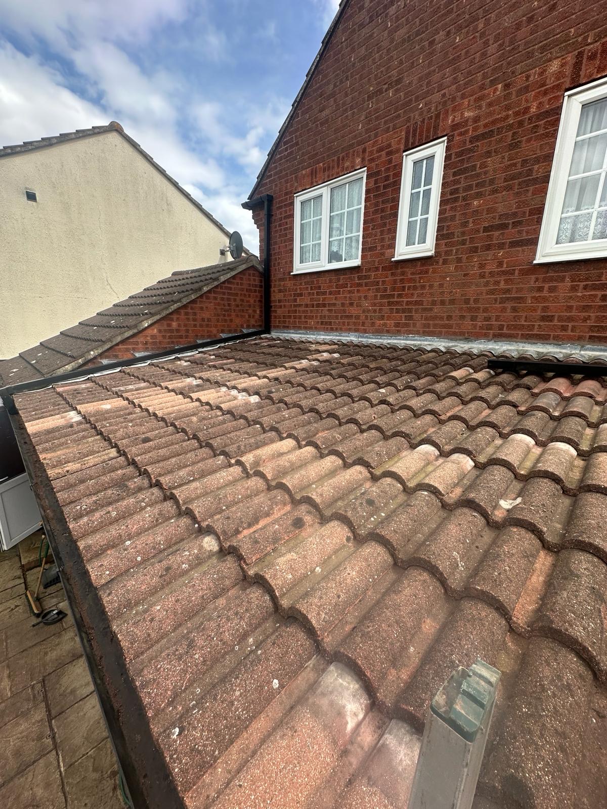 Freshly laid pantile roof with black trim against red brick gable