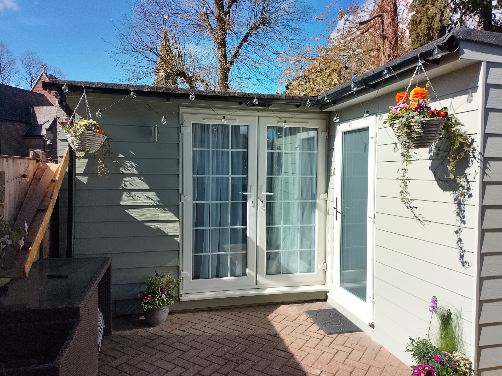 Neat felt-covered summer house roof with black guttering and fascias