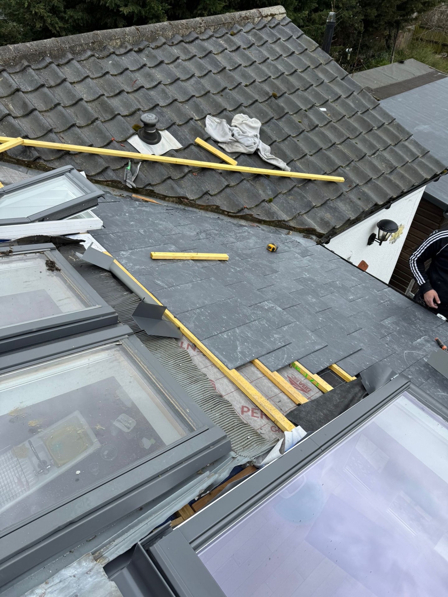 Slate roof installation in progress next to original tiled pitched roof