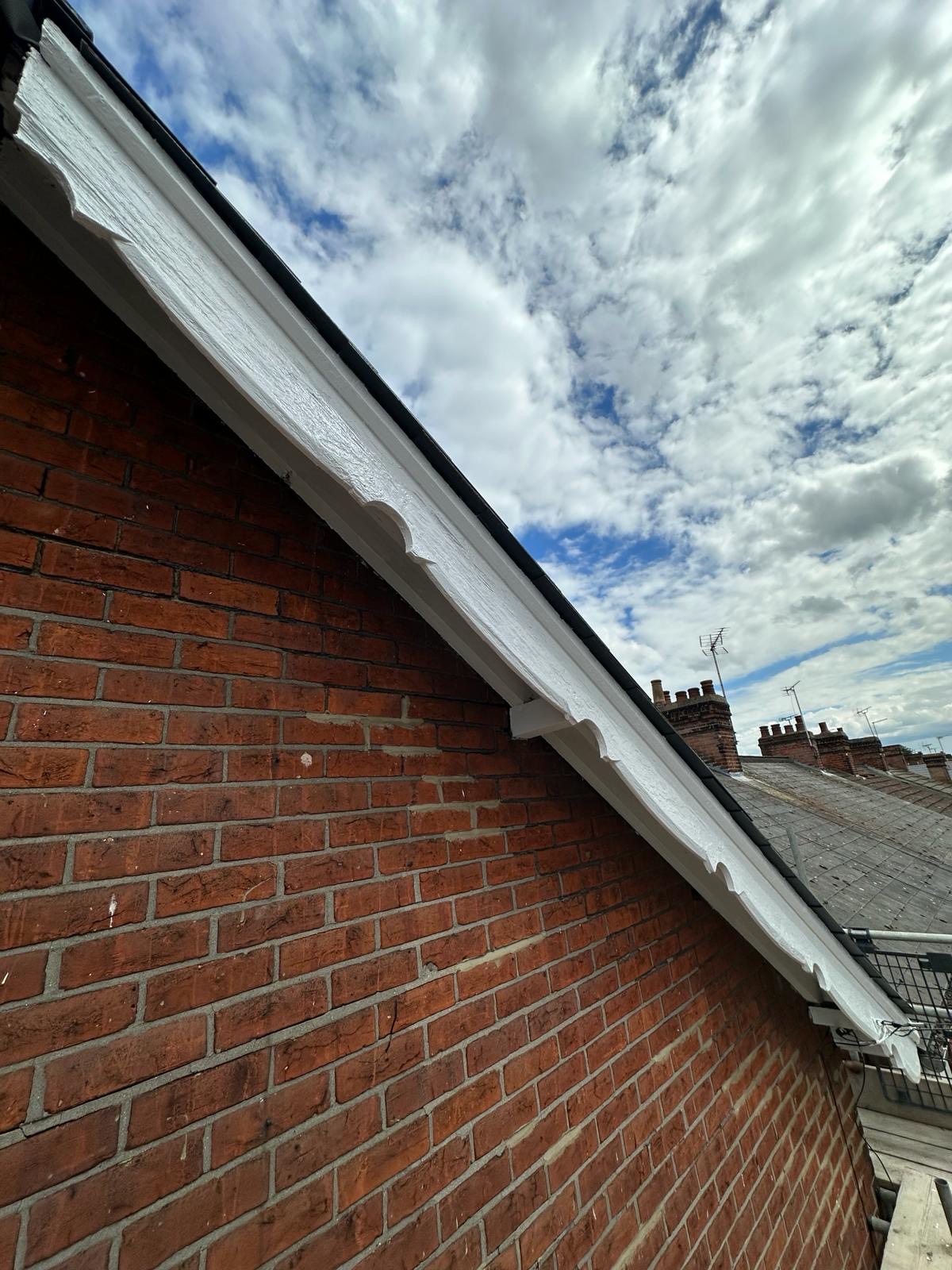 Freshly painted white bargeboard along a red brick gable end