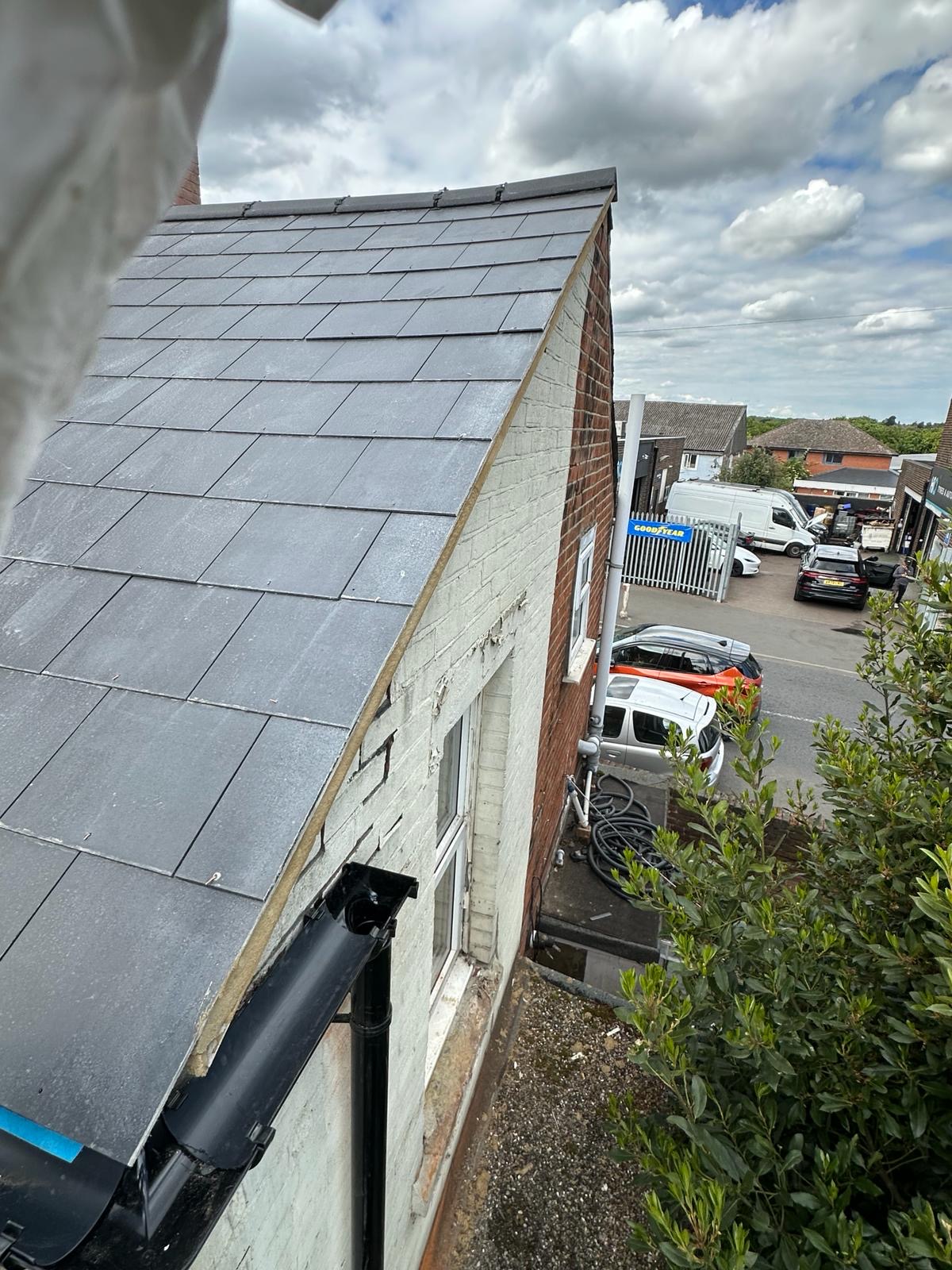 Gable-end slate roof looking out over rooftops on a bright day